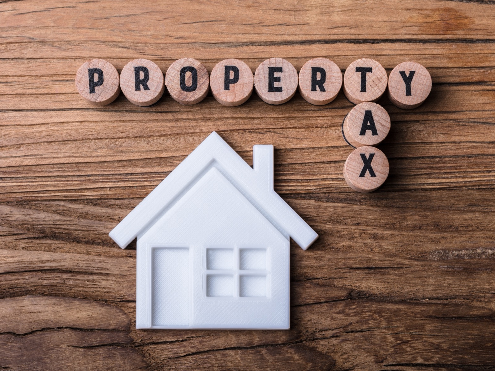 A model house beside wooden letters spelling property tax