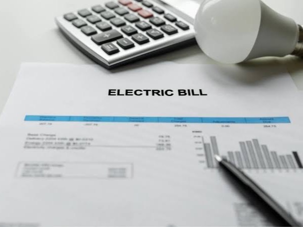 An electric bill on a desk with a calculator and a light bulb