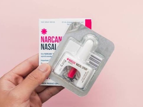 A hand holding a Narcan nasal spray package